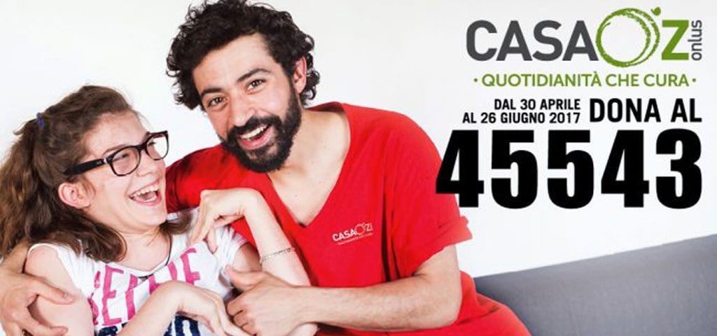 CasaOz - educatore abbraccia bambina sorridente, in posa per la campagna sms 2017