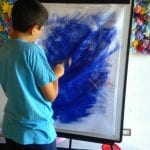 CasaOz - un bambino dipinge con impegno la propria opera nel laboratorio di pittura