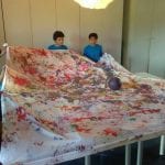 CasaOz - i bambini mostrano orgogliosi il frutto del laboratorio di pittura che si è appena concluso, sostenuti dall'educatore