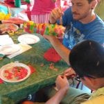 CasaOz - un educatore e un ragazzo alle prese con la creazione di una fioriera ricavata da una bottiglia di plastica durante il laboratorio creativo