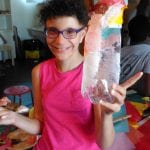 CasaOz - bambina sorridente mostra il proprio lavoro durante il laboratorio creativo