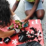CasaOz - bambino che riempie con le primule le fioriere ricavate dalle bottiglie di plastica durante il laboratorio creativo