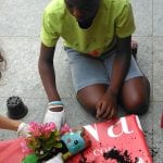 CasaOz - bambino che riempie con le primule le fioriere ricavate dalle bottiglie di plastica durante il laboratorio creativo