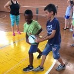 CasaOz - bambini divertiti alle prese con le basi del rugby, sotto lo sguardo attento di un'educatrice